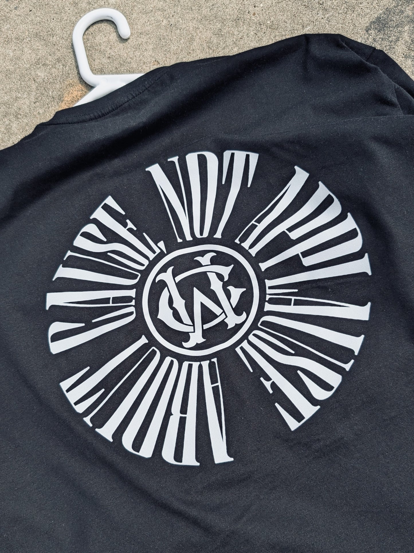 Close-up detail of WC tee’s back graphic text “About Cause Not Applause” in circular monogram style.