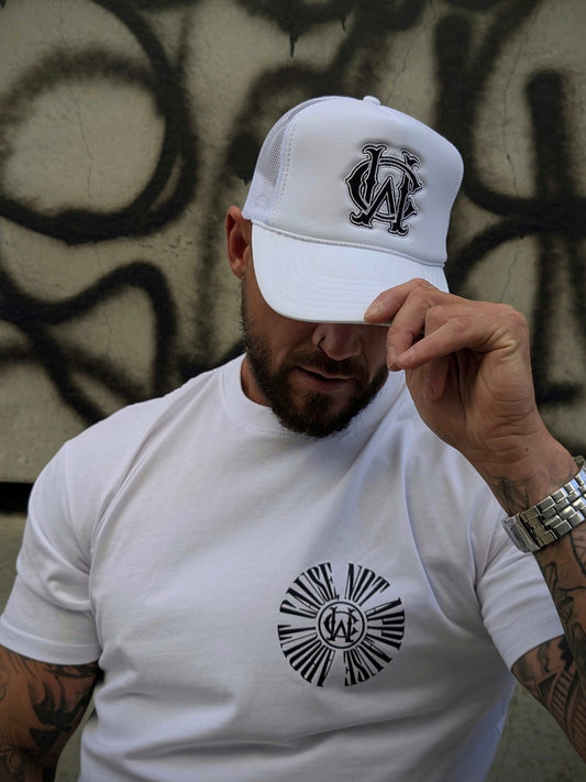 Model wearing white WC foam trucker hat in front of graffiti wall — classic streetwear close-up