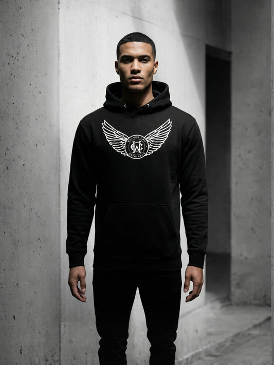 Person wearing a black hoodie with a logo in an urban setting
