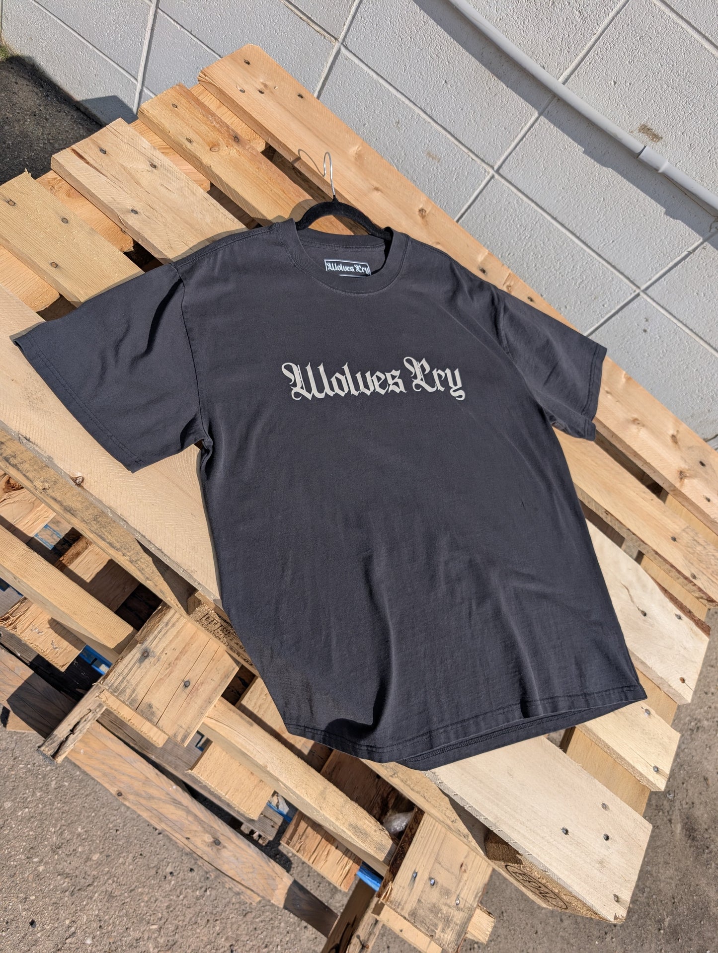 Flat lay of Wolves Cry Oversized Black Tee with cream camo logo — soft-washed black tone with subtle aged patina.