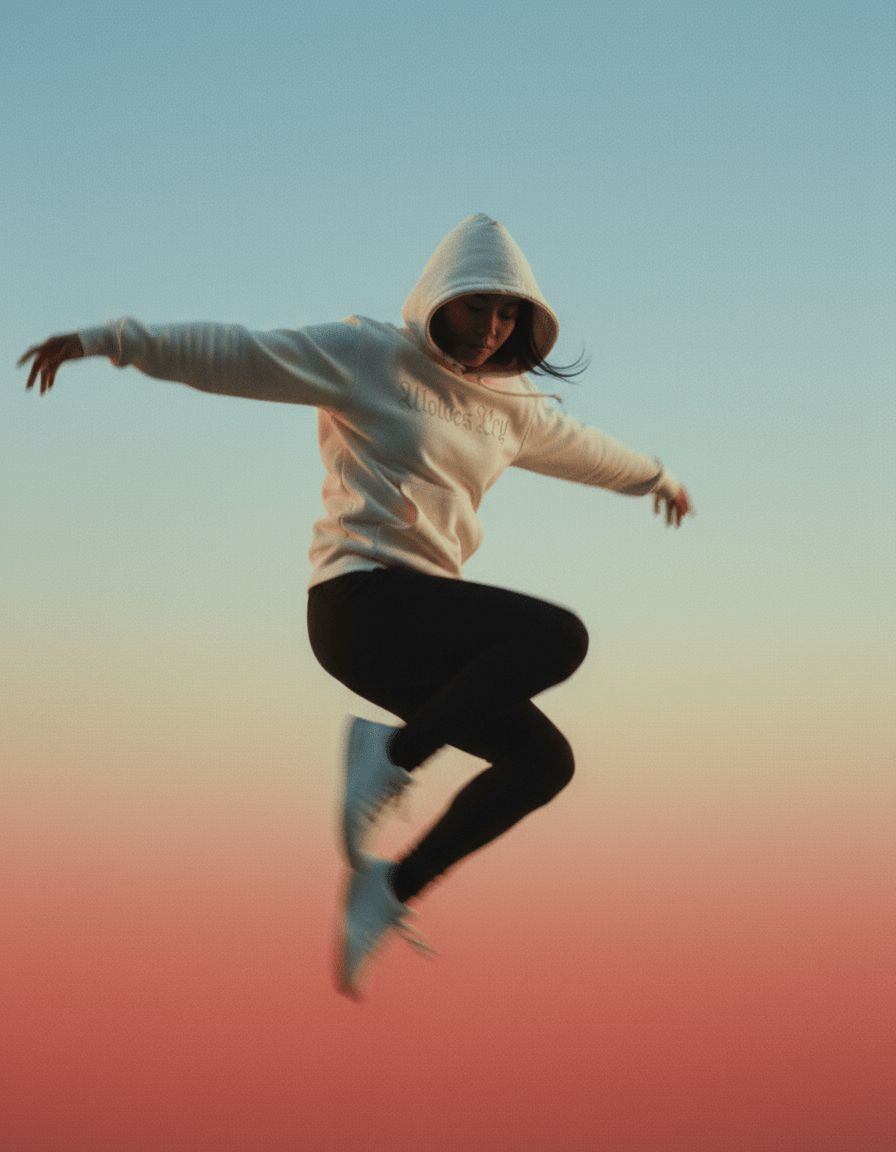 Model in a white wolves cry originals hoodie mid-jump against a sunset gradient backdrop- representing motion, freedom, and fearless streetwear design