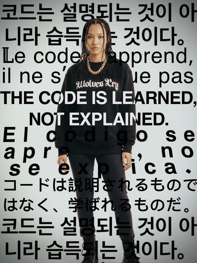 Wolves cry originals model wearing black hoodie with multilingual text background reading “ the code is learned, not explained” 