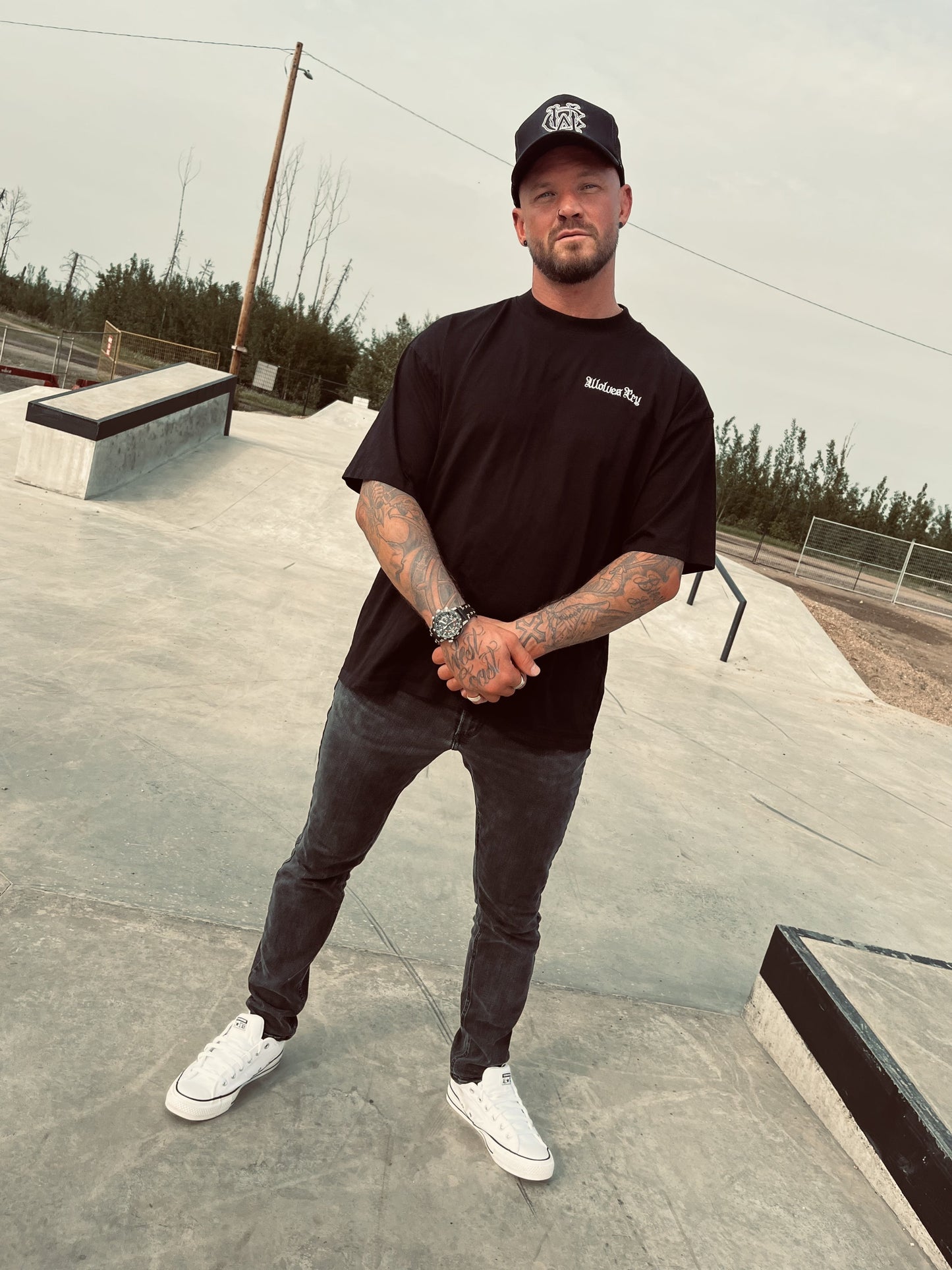 Front view of model wearing Wolves Cry black organic high neck tee with embroidered OG logo, styled in casual urban fit.