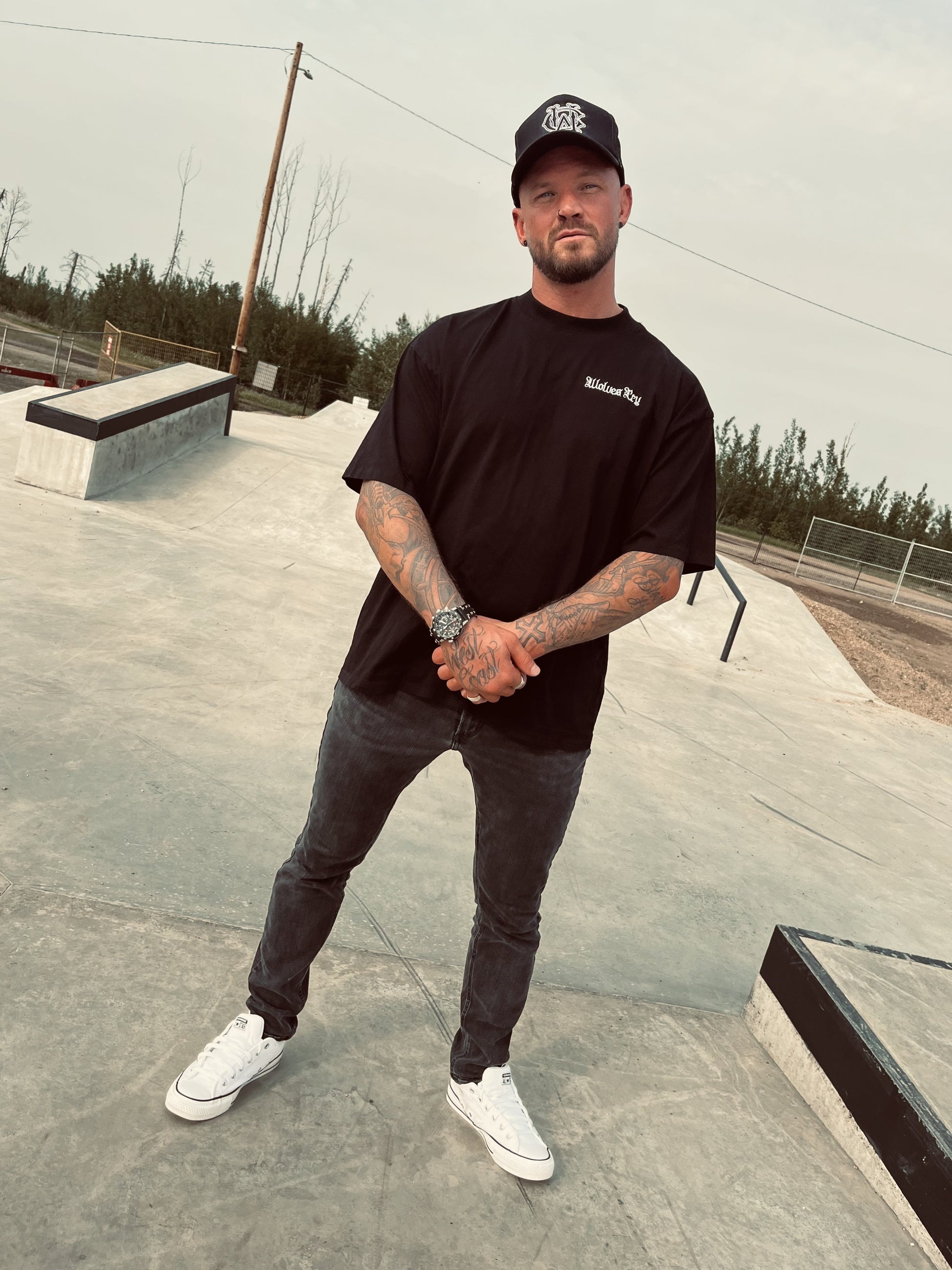 Front view of model wearing Wolves Cry black organic high neck tee with embroidered OG logo, styled in casual urban fit.