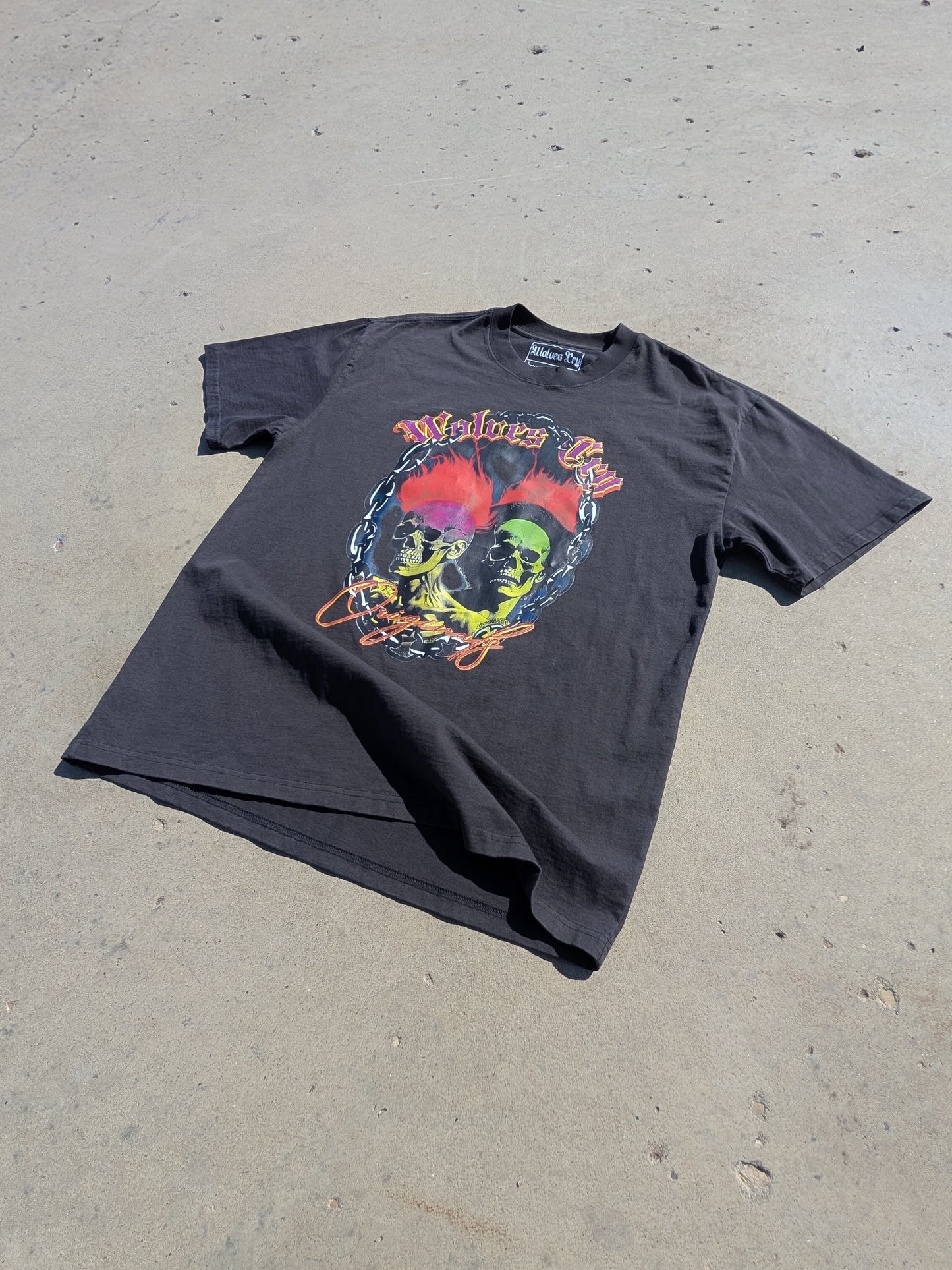 Oversized Megadeath Tee in Vintage Black by Wolves Cry Originals, flatlay under direct sunlight. Washed heavyweight cotton with neon skull flame print.