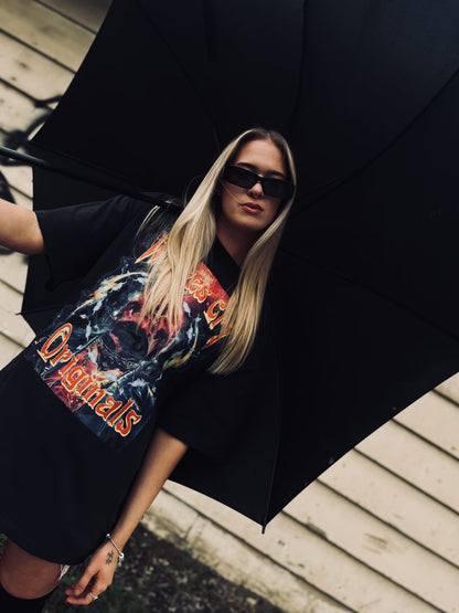 Female model in oversized Wolves Cry Universe Tee, holding an umbrella, styled with black sunglasses and streetwear accessories.