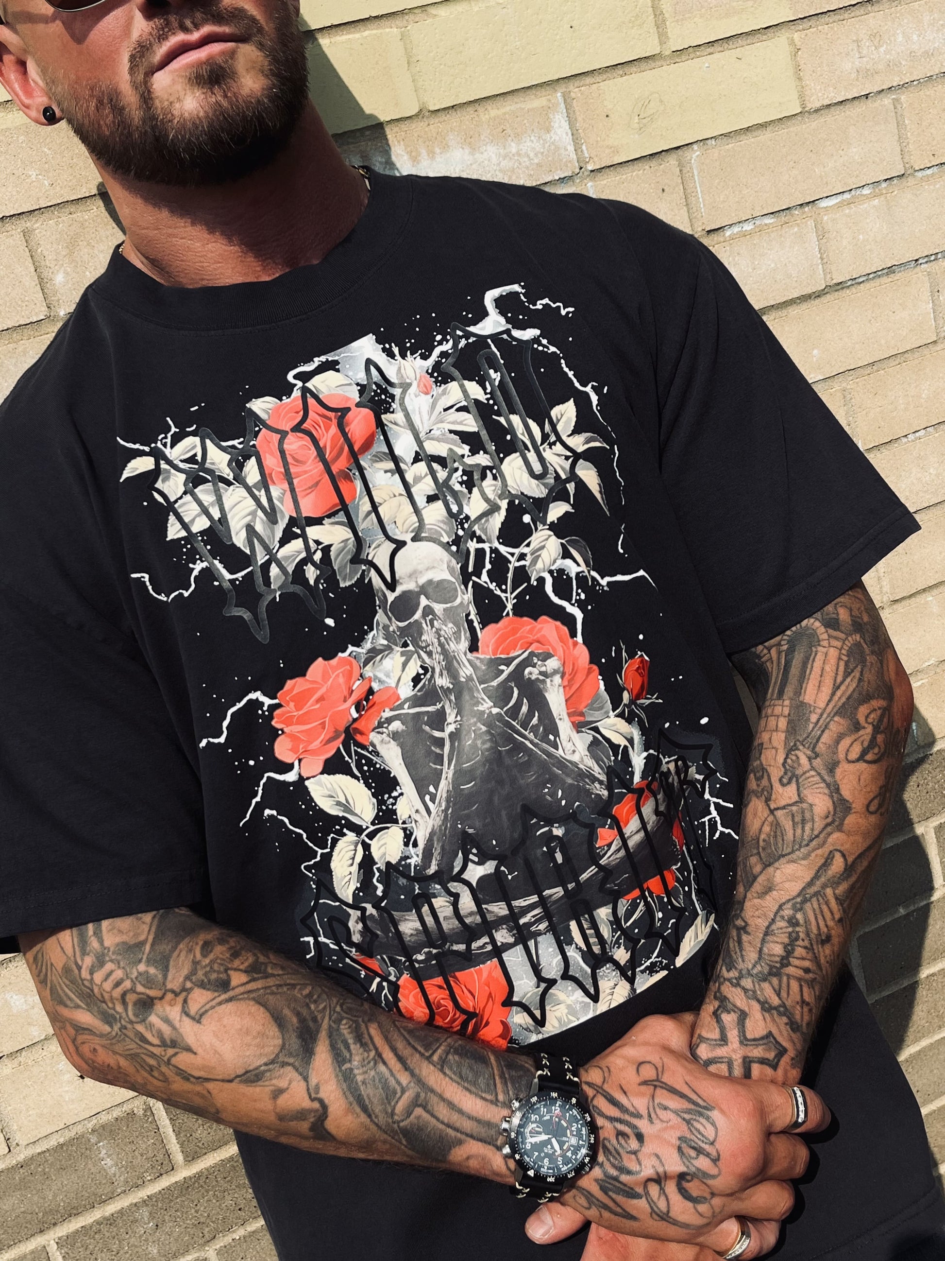 Detailed chest view of Wolves Cry Prayer Tee showing vivid roses, lightning, and gothic lettering print on faded black tee.
