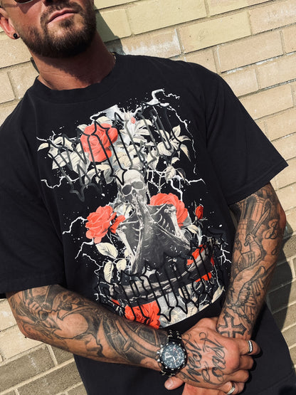 Detailed chest view of Wolves Cry Prayer Tee showing vivid roses, lightning, and gothic lettering print on faded black tee.