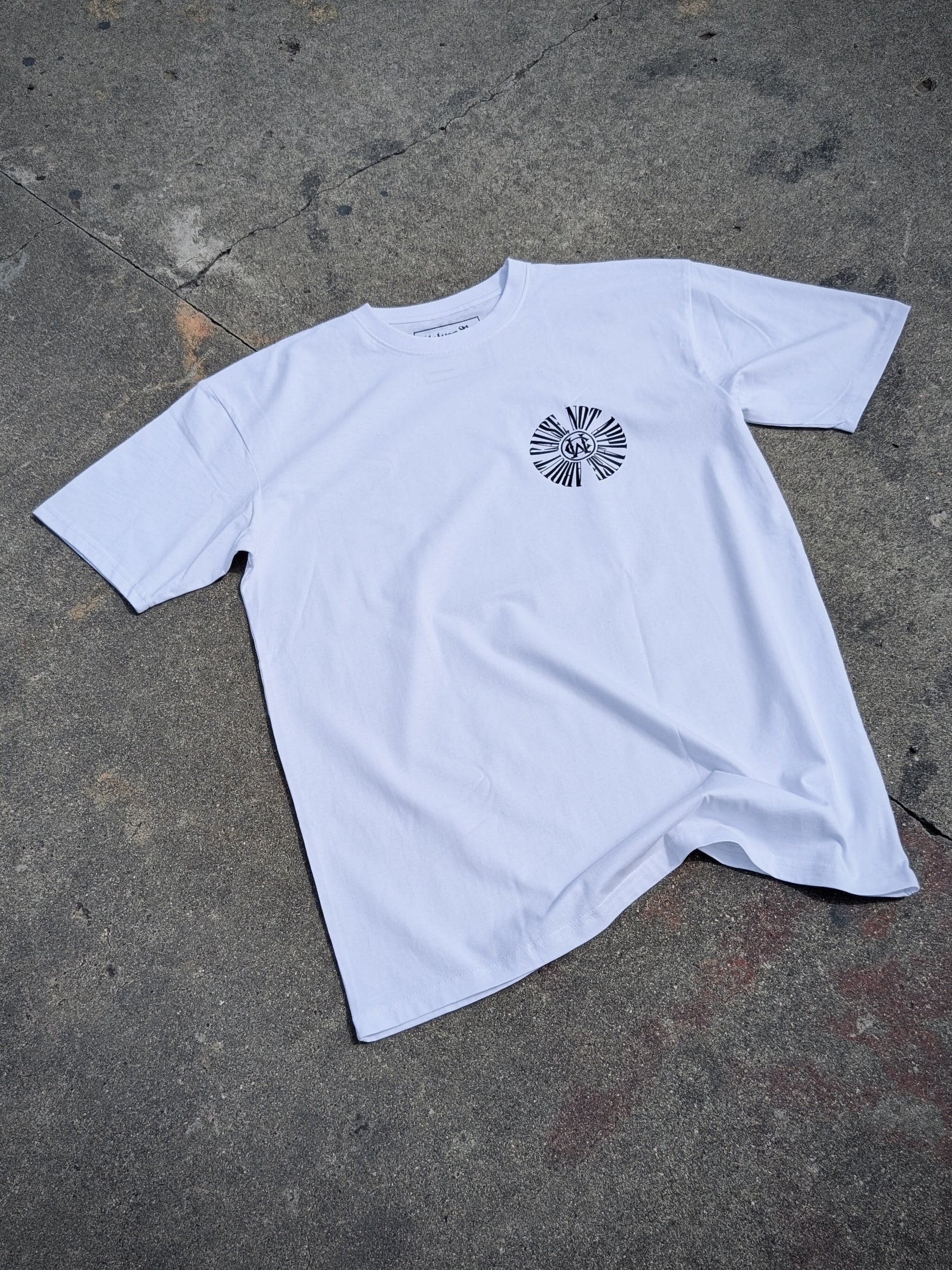 White graphic t-shirt featuring Wolves Cry circular monogram on left chest, laid flat on concrete