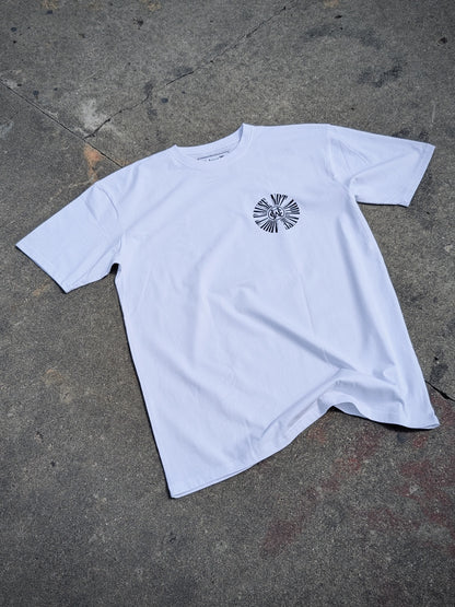 White graphic t-shirt featuring Wolves Cry circular monogram on left chest, laid flat on concrete