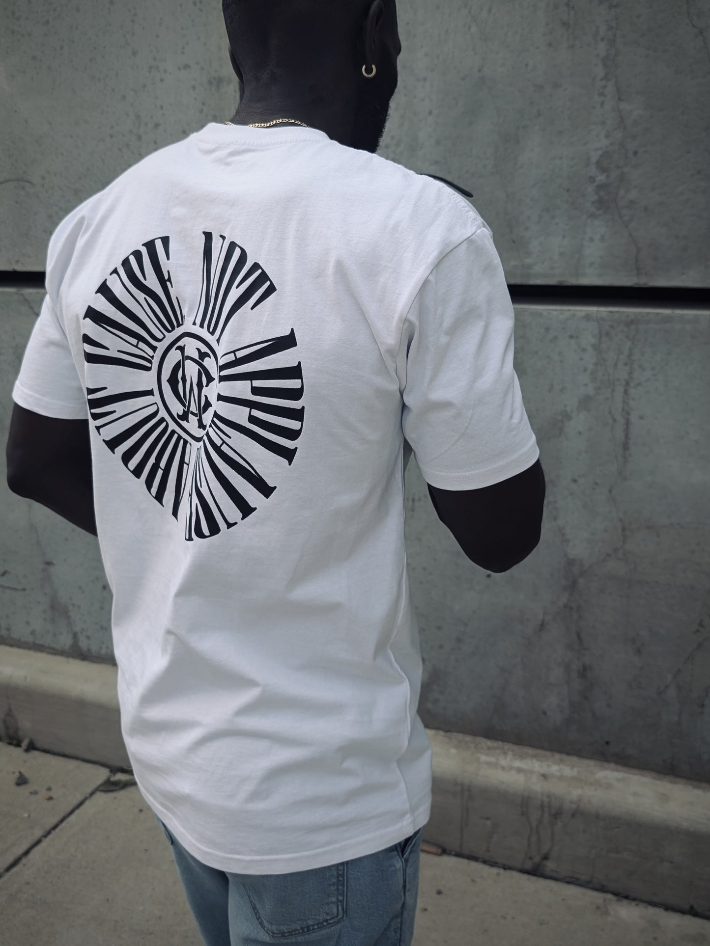 Back view of Wolves Cry tee in motion, displaying bold graphic “About Cause Not Applause” print