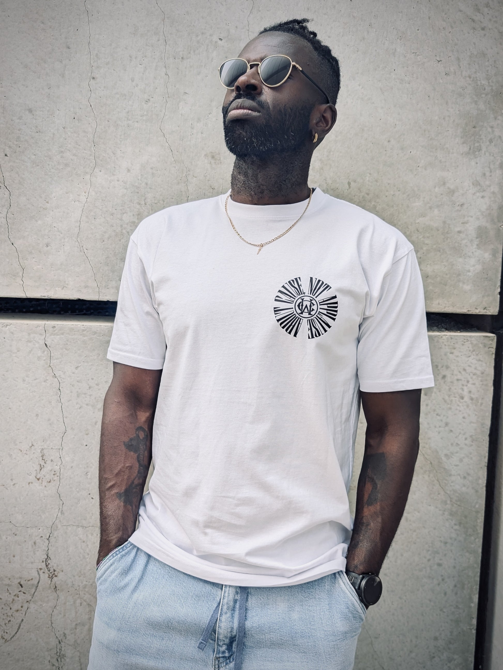 Model wearing Wolves Cry tee, showcasing chest monogram with minimal street styling and sunglasses