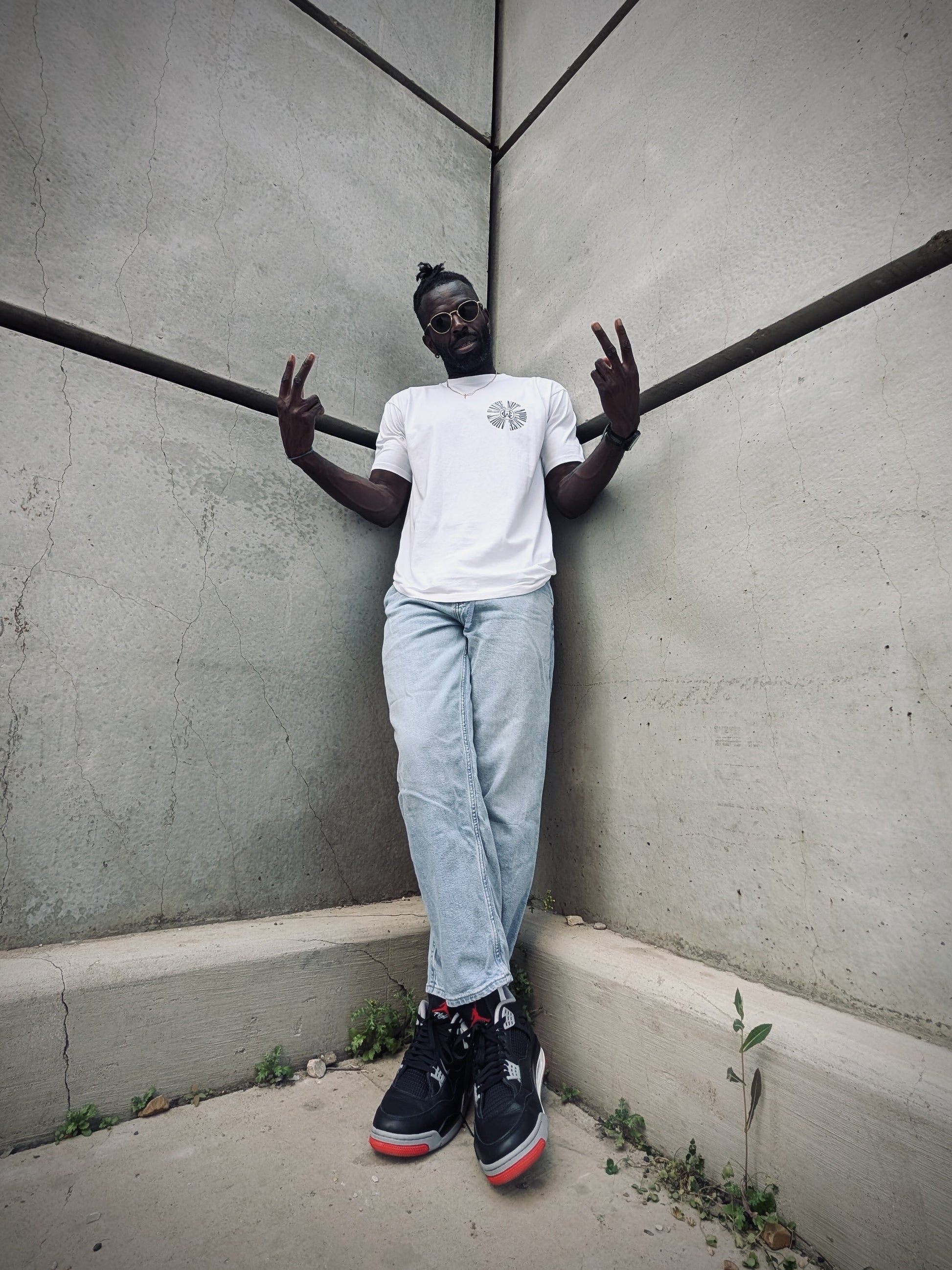 Full body shot of model wearing white streetwear graphic tee with light denim and Jordan sneakers