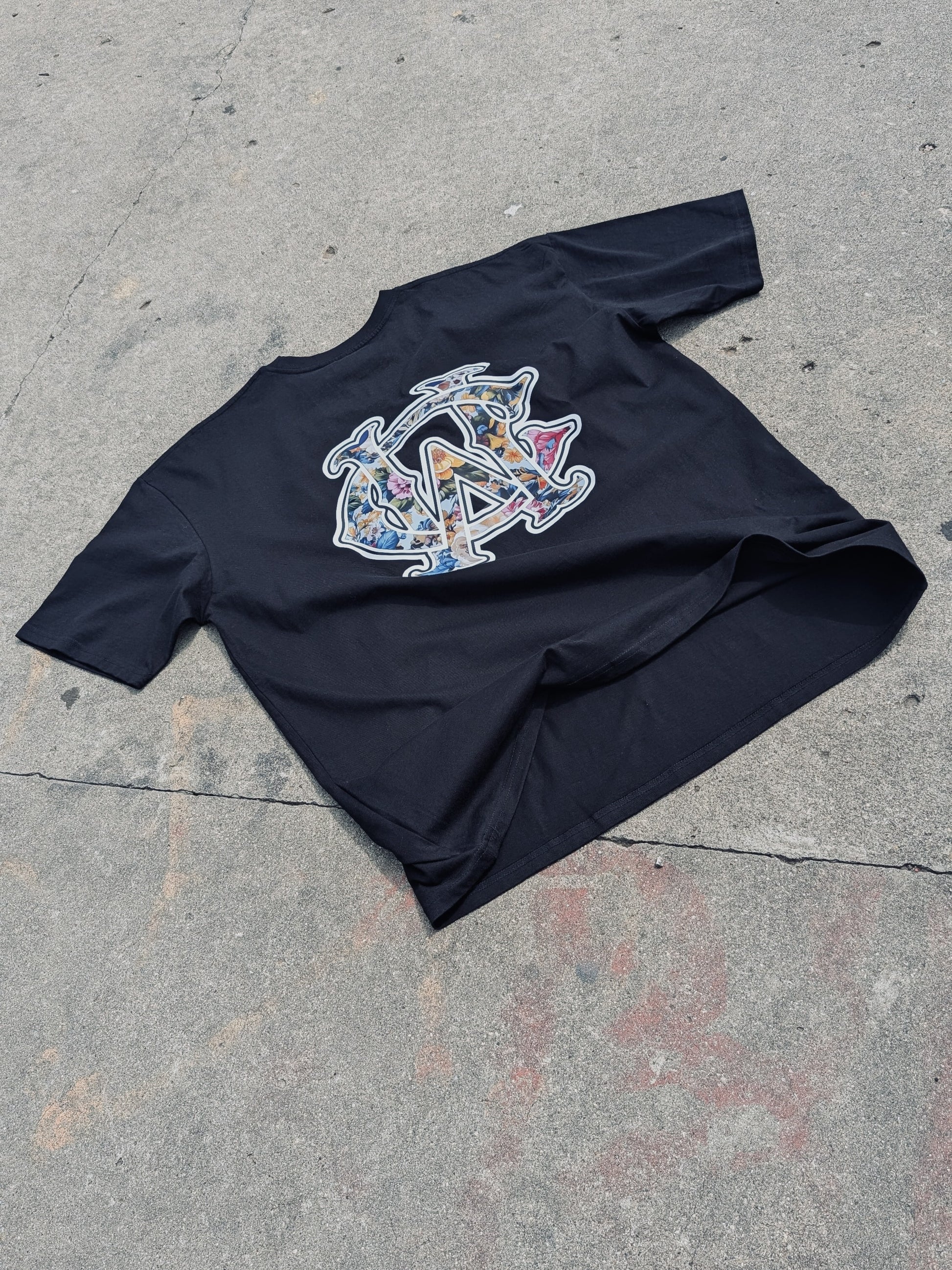 WC Shadow Floral Tee back flat lay showing floral WC monogram design on black cotton