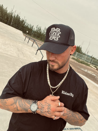 Model wearing the Wolves Cry Shadow Stitch Monogram Hat in black at skatepark – close-up angle showing detailed embroidery and streetwear chain styling.