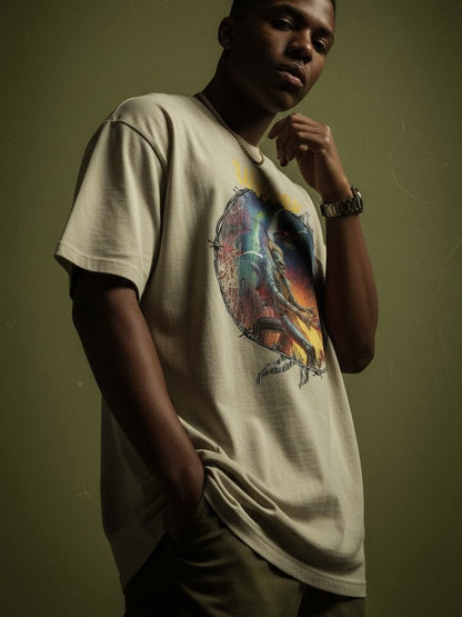 Model wearing the Wolves Cry Electric Symphony oversized tee in sage — art-forward streetwear style with warm tonal lighting and relaxed fit silhouette.
