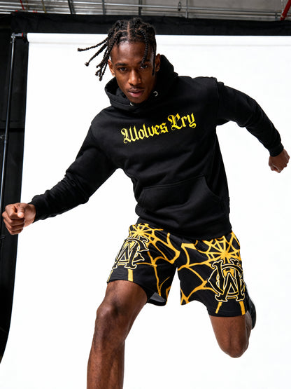 Person wearing a black hoodie with 'Wolves Cry' text and black shorts with yellow patterns.