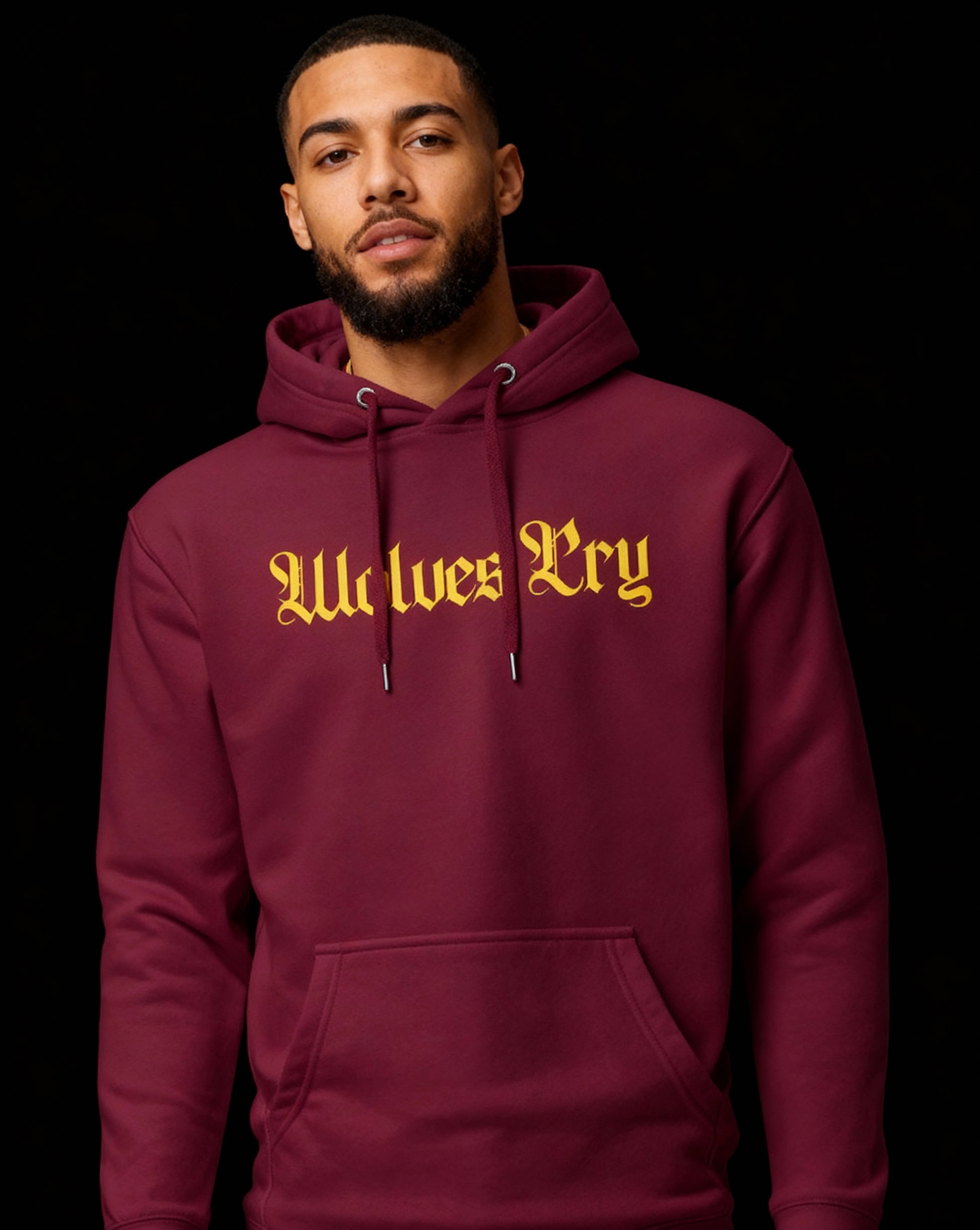 Studio portrait of model wearing Wolves Cry maroon hoodie with gold spellout logo — athletic influence meets refined street culture.