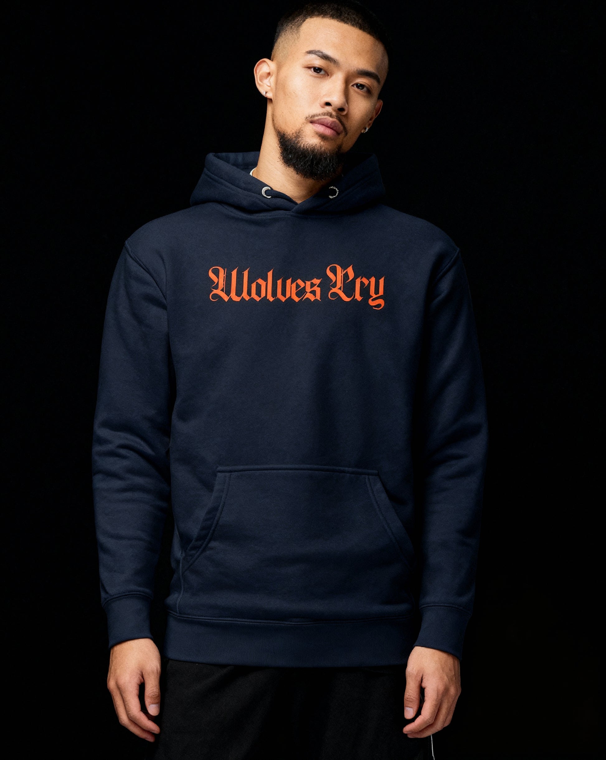 Close-up of Wolves Cry Everyday Spellout Hoodie embroidery — bright orange gothic logo on deep navy cotton, showcasing premium texture and detail.