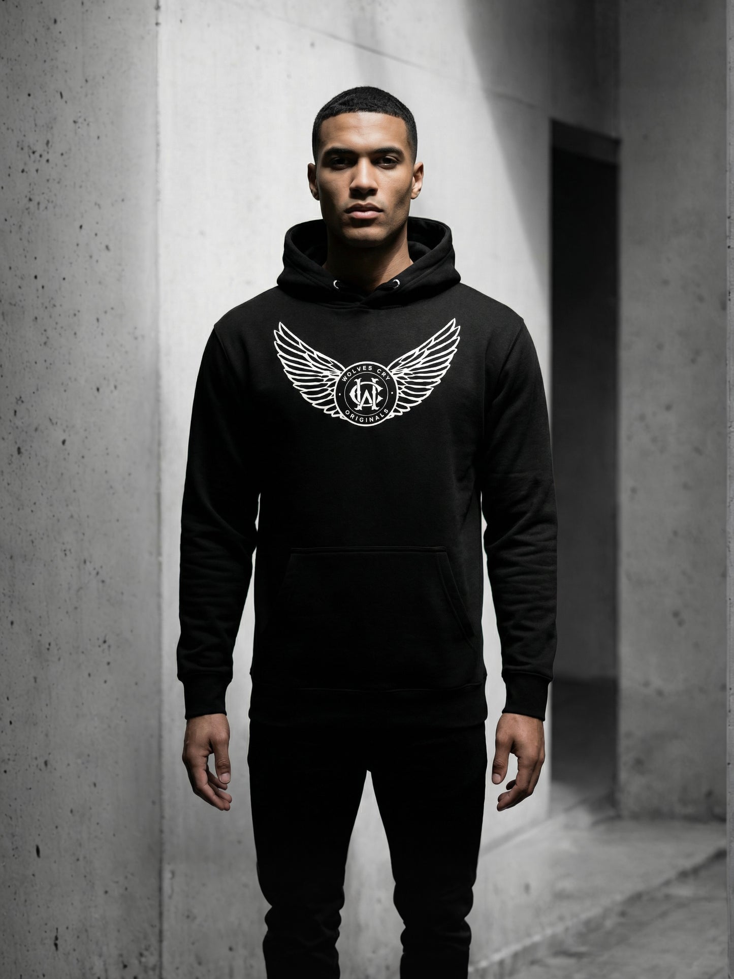 Person wearing a black hoodie with a logo in an urban setting