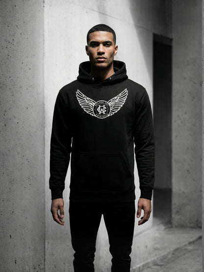 Person wearing a black hoodie with a logo in an urban setting