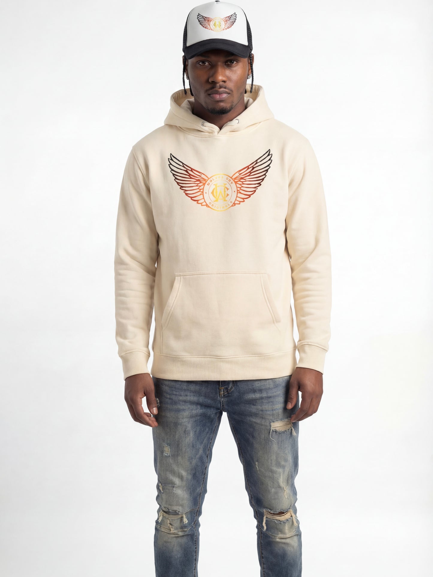Man wearing a wolves cry beige hoodie with a logo and distressed jeans on a white background