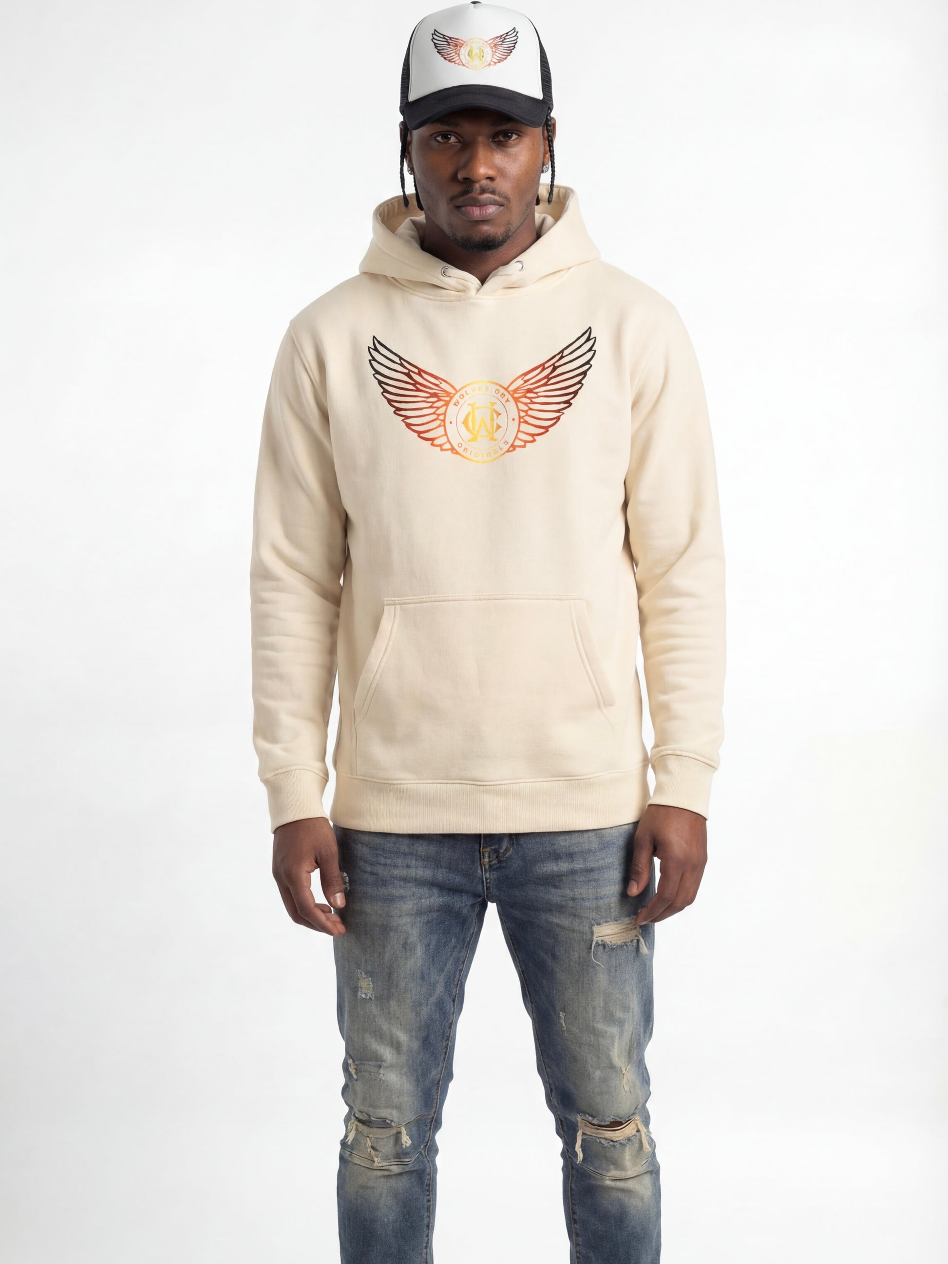 Man wearing a wolves cry beige hoodie with a logo and distressed jeans on a white background