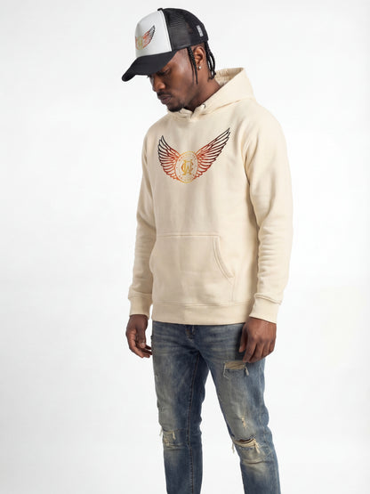 Man wearing a wolves cry originals beige hoodie with a logo and distressed jeans on a white background