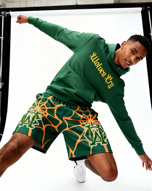 Model wearing Wolves Cry OG Green & Gold Spider Web mesh shorts — relaxed fit, movement-ready street athletic style.