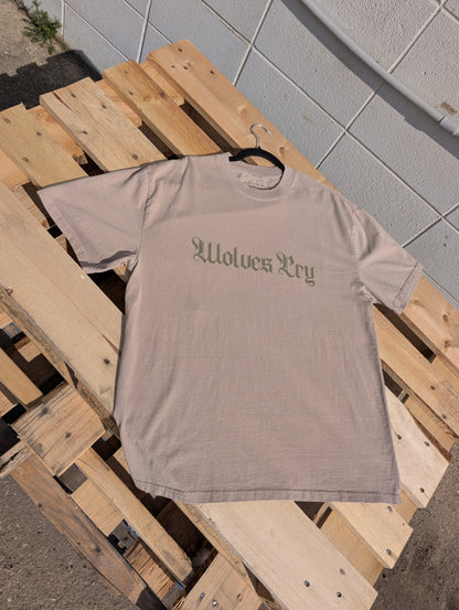 Flat lay of Wolves Cry Oversized Khaki Tee with subtle olive spell-out graphic — earthy neutral tones with a worn-in vintage wash.